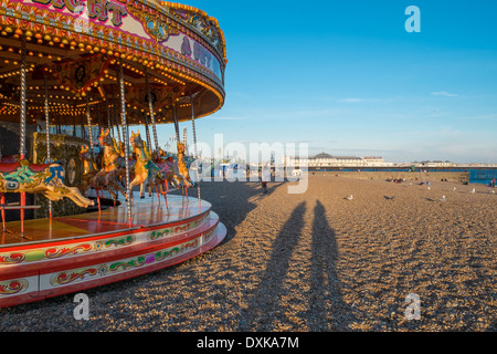 BRIGHTON, UK : Un carrousel traditionnel tour sur la célèbre plage de Brighton au coucher du soleil Banque D'Images