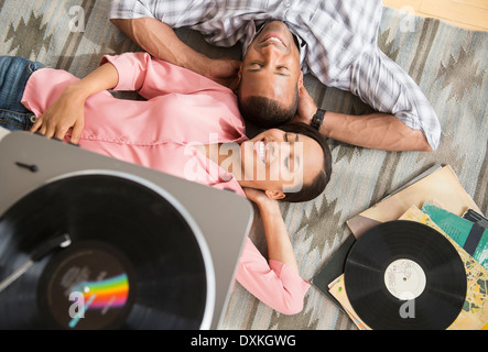 Couple heureux sur un tapis à l'écoute de record player Banque D'Images