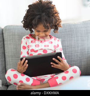 Close up of African American girl in pajamas using digital tablet Banque D'Images