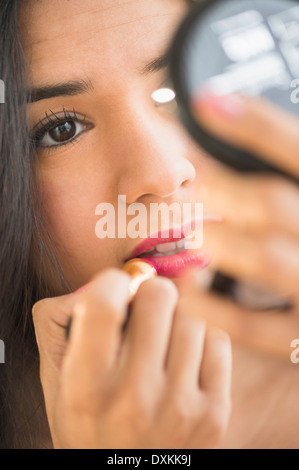 Close up of young woman applying lipstick en miroir compact Banque D'Images