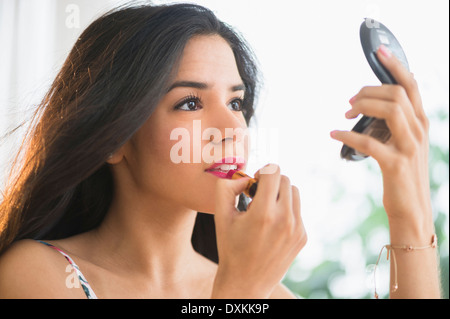 Young woman applying lipstick en miroir compact Banque D'Images