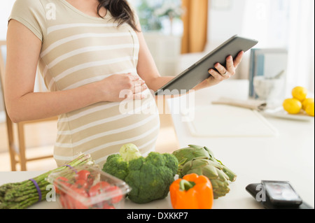 Japonais enceintes woman using digital tablet in kitchen Banque D'Images