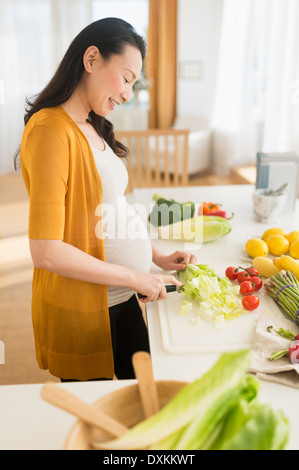 Femme japonaise enceinte émincer les légumes dans la cuisine Banque D'Images