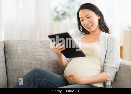 Enceinte Japanese woman using digital tablet on sofa Banque D'Images