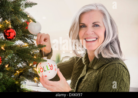 Portrait of Caucasian woman hanging ornaments on Christmas Tree Banque D'Images