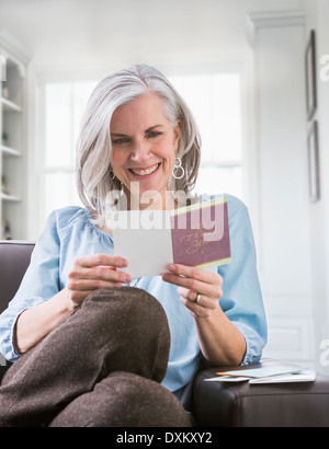 La lecture de la carte Happy woman on sofa Banque D'Images