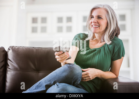 Happy woman watching TV on sofa Banque D'Images