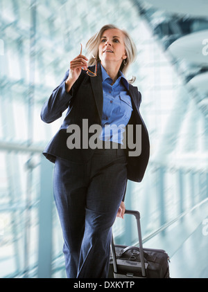 Caucasian businesswoman rushing with suitcase in airport Banque D'Images