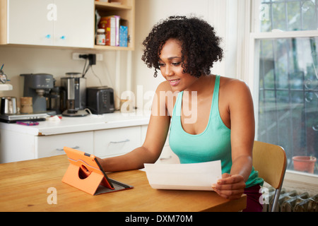 Mixed Race woman using digital tablet in kitchen Banque D'Images