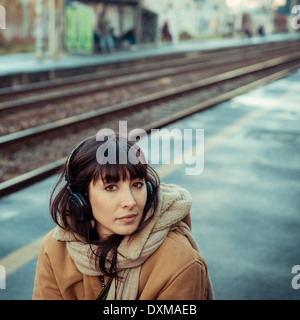 Belle jeune femme d'écouter de la musique dans le casque d'hiver ville Banque D'Images