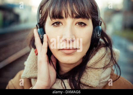 Belle jeune femme d'écouter de la musique dans le casque d'hiver ville Banque D'Images