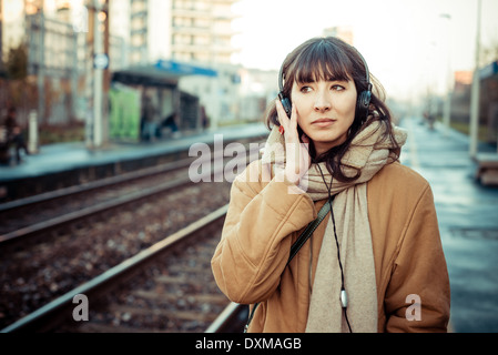 Belle jeune femme d'écouter de la musique dans le casque d'hiver ville Banque D'Images