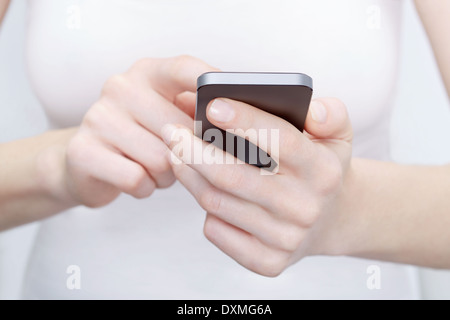 Portrait de femme en blanc à l'aide d'un smartphone moderne Banque D'Images