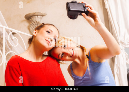 Deux filles faisant eux-mêmes photo dans une chambre Banque D'Images