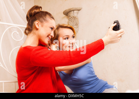 Deux filles faisant eux-mêmes photo dans une chambre Banque D'Images