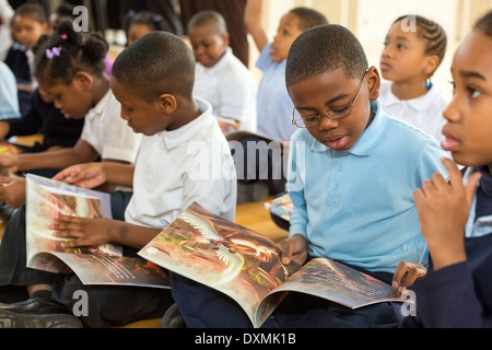 La maternelle et les premières élèves de l'école élémentaire de Detroit Chrysler lire un livre. Banque D'Images