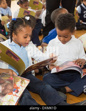 La maternelle et les premières élèves de l'école élémentaire de Detroit Chrysler lire un livre. Banque D'Images