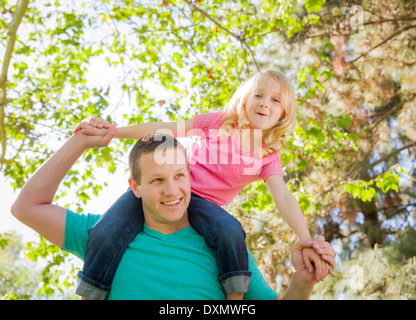 Cute Young Girl Piggyback Rides sur ses épaules de papas à l'extérieur du parc. Banque D'Images