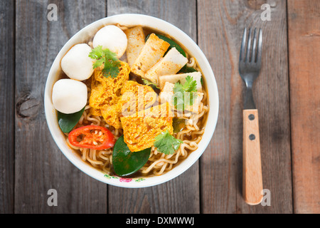 Curry épicé nouilles potage instantané avec la fourchette sur la table à manger en bois. Douce chaude avec de la fumée. Banque D'Images