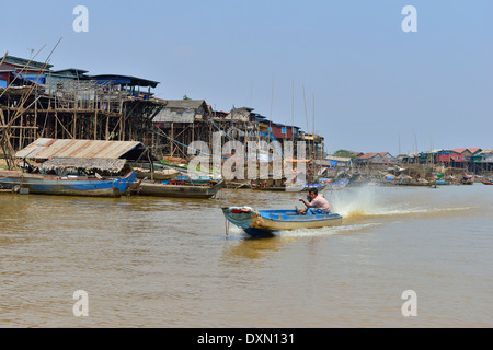 Bateau à grande vitesse à longue queue qui ferriait les produits le long de la rivière avec des maisons sur pilotis sur le rivage jusqu'au lac Tonle SAP, au Cambodge, en Asie du Sud-est Banque D'Images