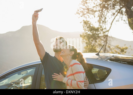 Heureux couple taking self-portrait with camera phone parking extérieur Banque D'Images