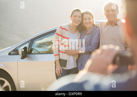 Man photographing family outside car Banque D'Images