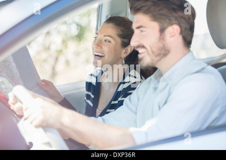 Heureux couple with map driving in car Banque D'Images