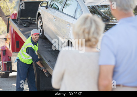 Senior couple watching roadside mechanic préparer pour remorquer voiture Banque D'Images