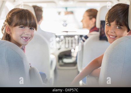 Portrait of happy brother and sister in back seat of car Banque D'Images