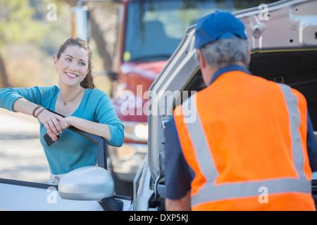 Reconnaissant woman watching roadside mechanic voiture fix Banque D'Images