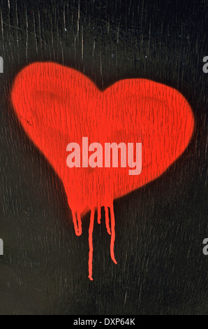 Un cœur rouge peint sur un fond en bois noir Banque D'Images