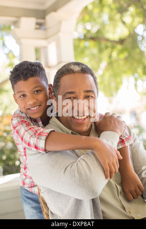 Close up portrait of smiling grandfather and grandson hugging on porch Banque D'Images