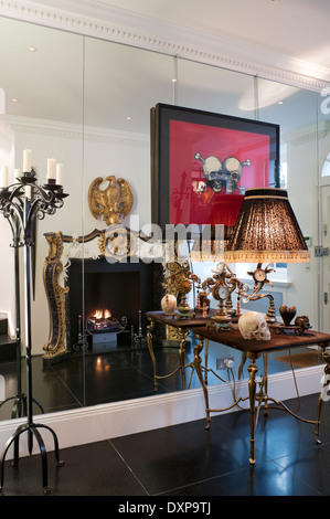 Table par Mark Brazier-Jones Trudi contre mur de miroirs avec la réflexion d'une cheminée de style empire doré par Nicholas Haslam Banque D'Images