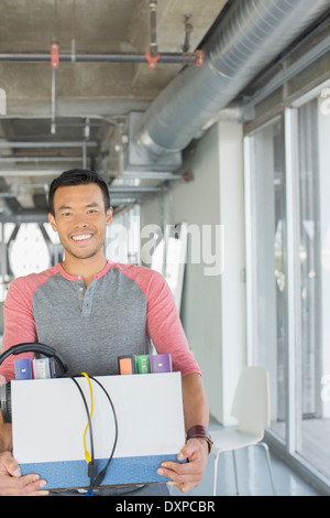 Portrait of happy businessman carrying box de biens in office Banque D'Images