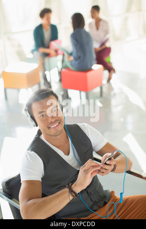 Portrait of businessman listening to music on headphones avec mp3 player Banque D'Images