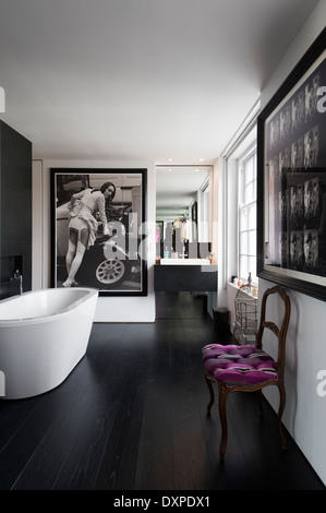 Salle de bains moderne avec des affiches photographiques noir et blanc et blanc baignoire sur pieds Banque D'Images