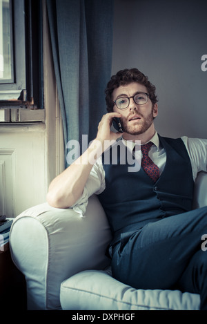 Mode attrayant élégant hipster homme au téléphone à la maison Banque D'Images