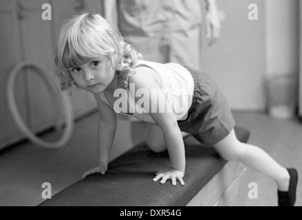 Berlin, DDR, petite fille dans une Kindertagesstaette gymnastique n sur un fort Banque D'Images