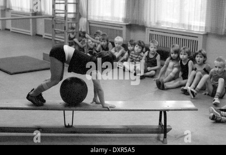 Berlin, DDR, petite fille monte dans l'éducation physique sur un banc sur un ballon Banque D'Images