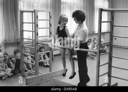 Berlin, DDR, petite fille ne la gymnastique en éducation physique à la barre fixe Banque D'Images