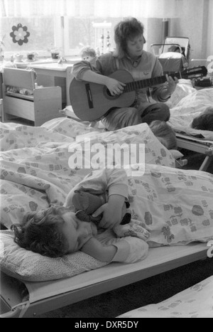 Berlin, DDR, enseignant de maternelle ensemble contre le poil des enfants à la guitare Banque D'Images