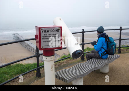 Un randonneur mâle marchant sur le sentier côtier de Cleveland Way, qui donne sur la jetée de Saltburn depuis la promenade du haut, un matin brumeux. North Yorkshire, Angleterre. ROYAUME-UNI Banque D'Images