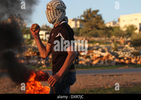 Ramallah, Palestinien. Mar 28, 2014. Un manifestant palestinien utilise une élingue à lancer des pierres en direction de soldats israéliens lors d'une manifestation contre la colonie juive d'Ofra, dans le village de Silwad, le 28 mars 2014 près de Ramallah Un palestinan arrestation et cinq Palestiniens ont été blessés par balles en caoutchouc et des gaz lacrymogènes, et, au cours de l'vendredi des affrontements entre manifestants palestiniens du village de Silwad, près de Ramallah et l'armée israélienne. © Museitef NurPhoto Abdalkarim //ZUMAPRESS.com/Alamy Live News Banque D'Images