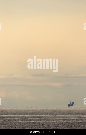 Seule l'huile écossais / gaz rig loin à l'horizon contre un ciel voilé ciel du soir. Banque D'Images