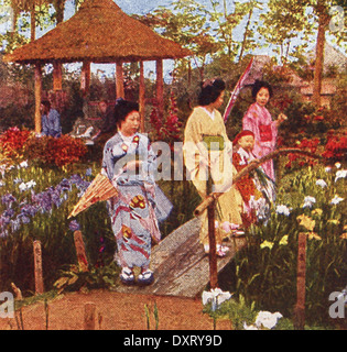 Cette scène au Japon remonte à 1909. Il montre trois femmes et un enfant dans un jardin de fleurs. Banque D'Images