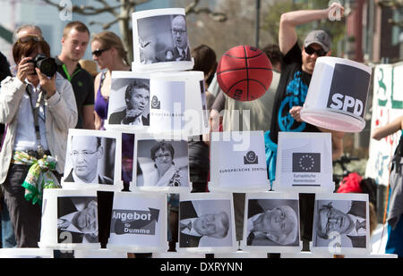 Un participant d'un anti-EZB-jette une démonstration de basket-ball rouge contre un mur en plastique seaux, qui sont imprimées avec des politiciens, des banquiers et des chefs de l'économie de Francfort/Main, Allemagne, 30 mars 2014. Plusieurs centaines de manifestants participer à la manifestation dans le contexte de l'initiative "Blockupy", une promenade le long de la construction du nouveau site EZB. Photo : Boris Roessler/dpa Banque D'Images