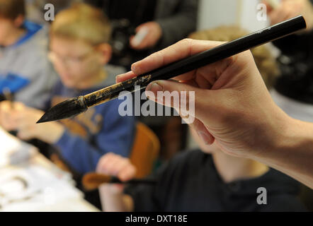 L'artiste japonais et maître de calligraphie HARU (L) indique à 6e année Les élèves de l'école comment tenir un pinceau pendant une leçon en calligraphie à Teltow, Allemagne, 24 mars 2014. HARU est l'enseignement aux élèves les secrets de l'écriture des caractères japonais. Les leçons de calligraphie est partie d'un programme culturel, "l'échange culturel germano-japonais en images", qui met l'accent sur les échanges culturels entre l'Allemagne et le Japon. Le programme se termine par une exposition et la visite d'une délégation de l'artistes japonais dans Teltowq fin mars. Photo : Bernd Settnik/ZB/dpa Banque D'Images