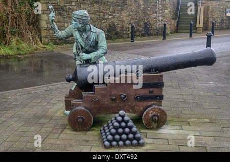 Une sculpture commémorant le passé maritime de whitehaven dans le port. Un marin frappant un canon Banque D'Images