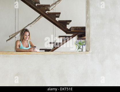 Portrait of smiling woman texting on cell phone at table Banque D'Images