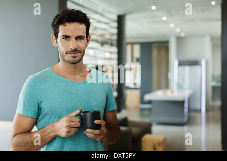 Portrait of smiling man drinking coffee at home Banque D'Images